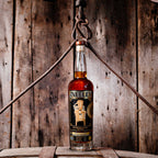 Bottle of Neeley Family Distillery Bottled-In-Bond Whiskey over a barrel