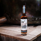 Bottle of Hidden Barn Kentucky Straight Bourbon Whiskey on a wooden surface with a blurred background