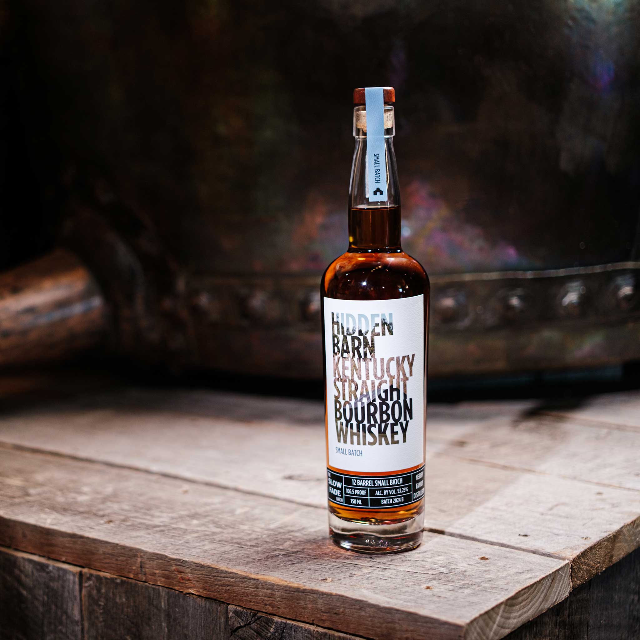 Bottle of Hidden Barn Kentucky Straight Bourbon Whiskey on a wooden surface with a blurred background