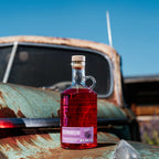 Bottle of Neeley Family Distillery Southern Blackberry Moonshine on a rusty vehicle with a blue sky background