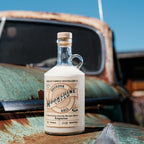 Bottle of Neeley Family Distillery Moonshine Cream Liqueur on a rusty vehicle with a blue sky background