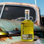 Bottle of Neeley Family Distillery Moonshine on a rusty vehicle with a blue sky background