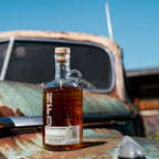 Bottle of Neeley Family Distillery Sweet Tea Moonshine on a rusty vehicle with a blue sky background