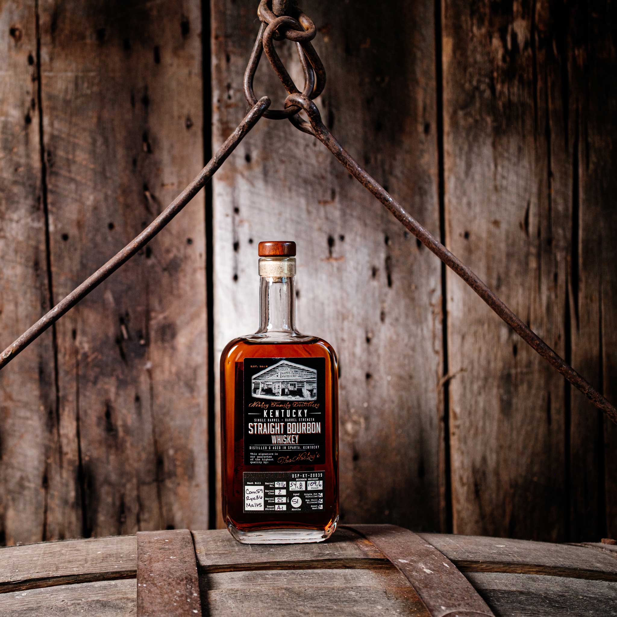 Bottle of Neeley Family Distillery Single Barrel Wheated Whiskey over a barrel