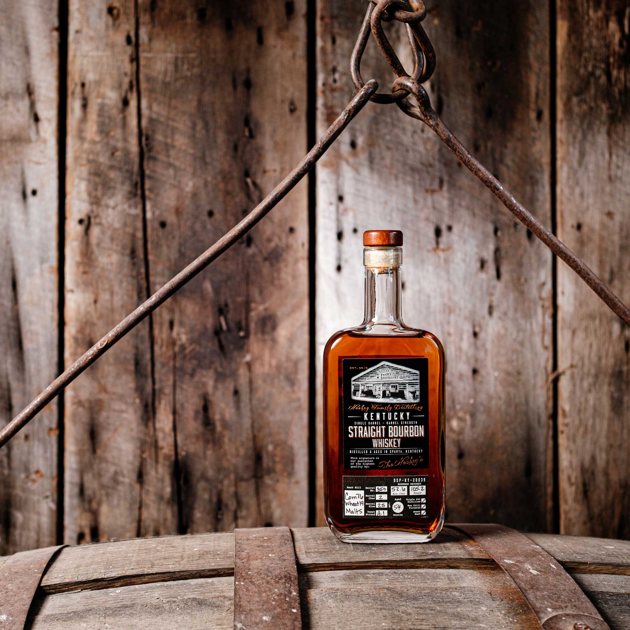 Bottle of Neeley Family Distillery Single Barrel Wheated Whiskey over a barrel