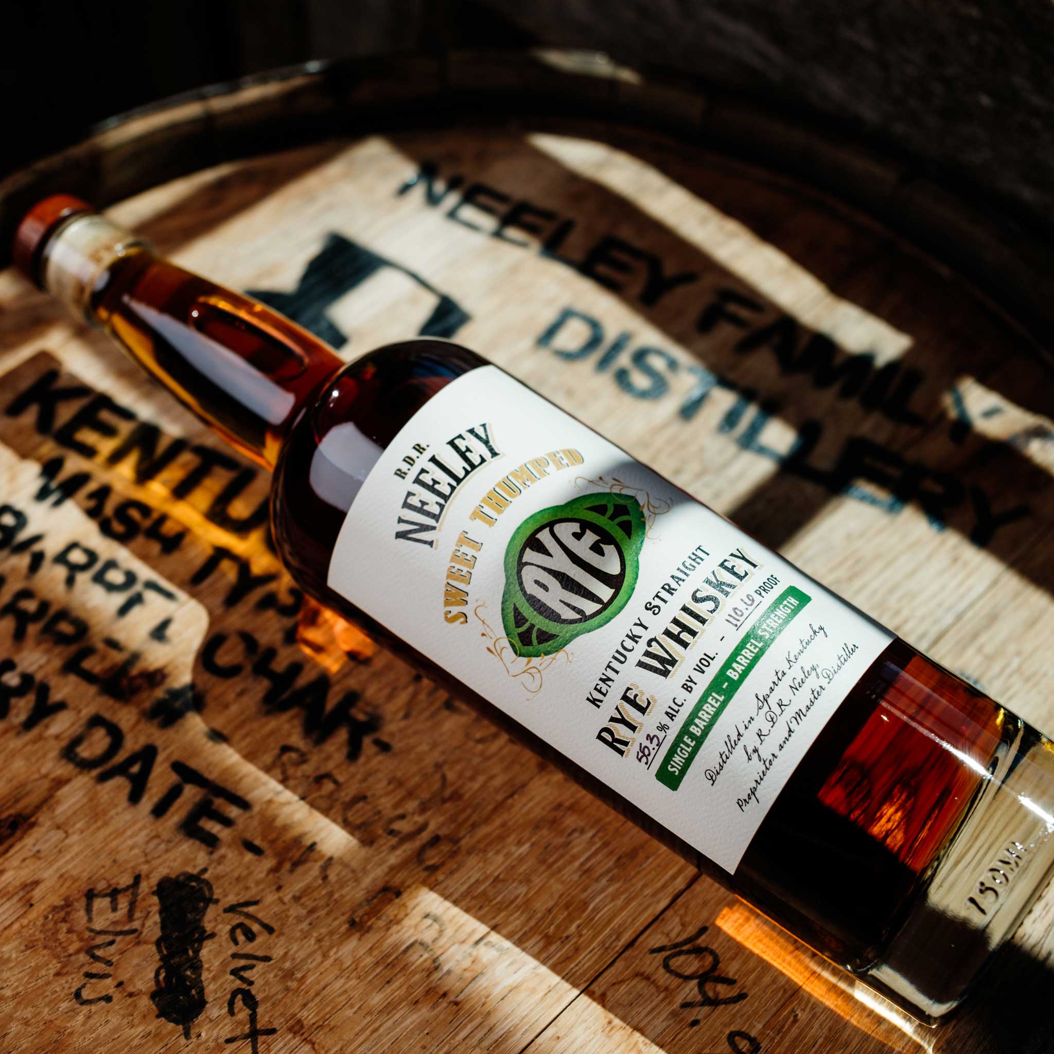 Bottle of Neeley Family Distillery Sweet Thumped Rye Whiskey Over A Wooden Barrel