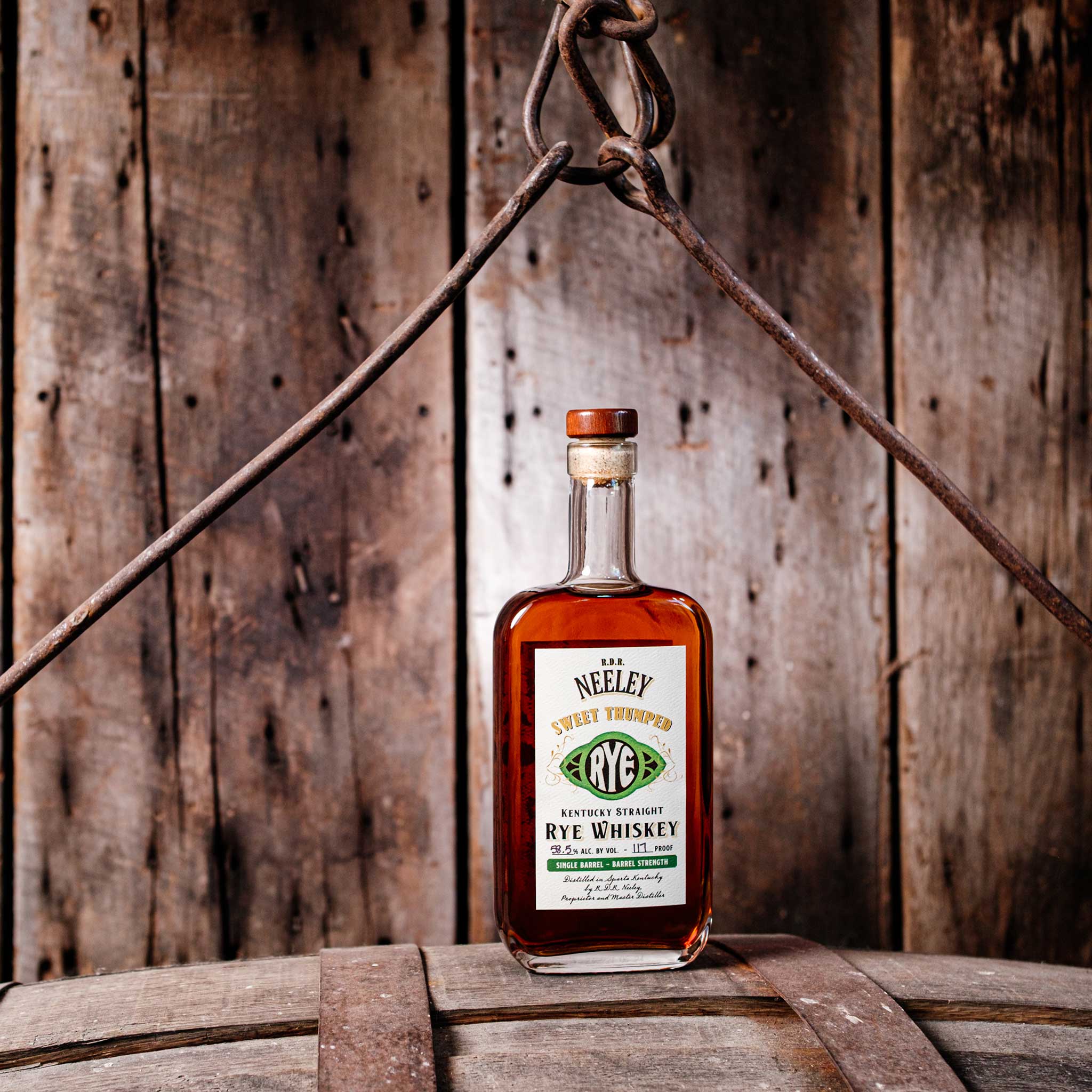 Bottle of Neeley Family Distillery Sweet Thumped Rye Whiskey Over A Wooden Barrel