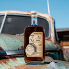 Bottle of Neeley Family Distillery Kentucky Salted Caramel Flavored Whiskey on a rusty vehicle with a blue sky background