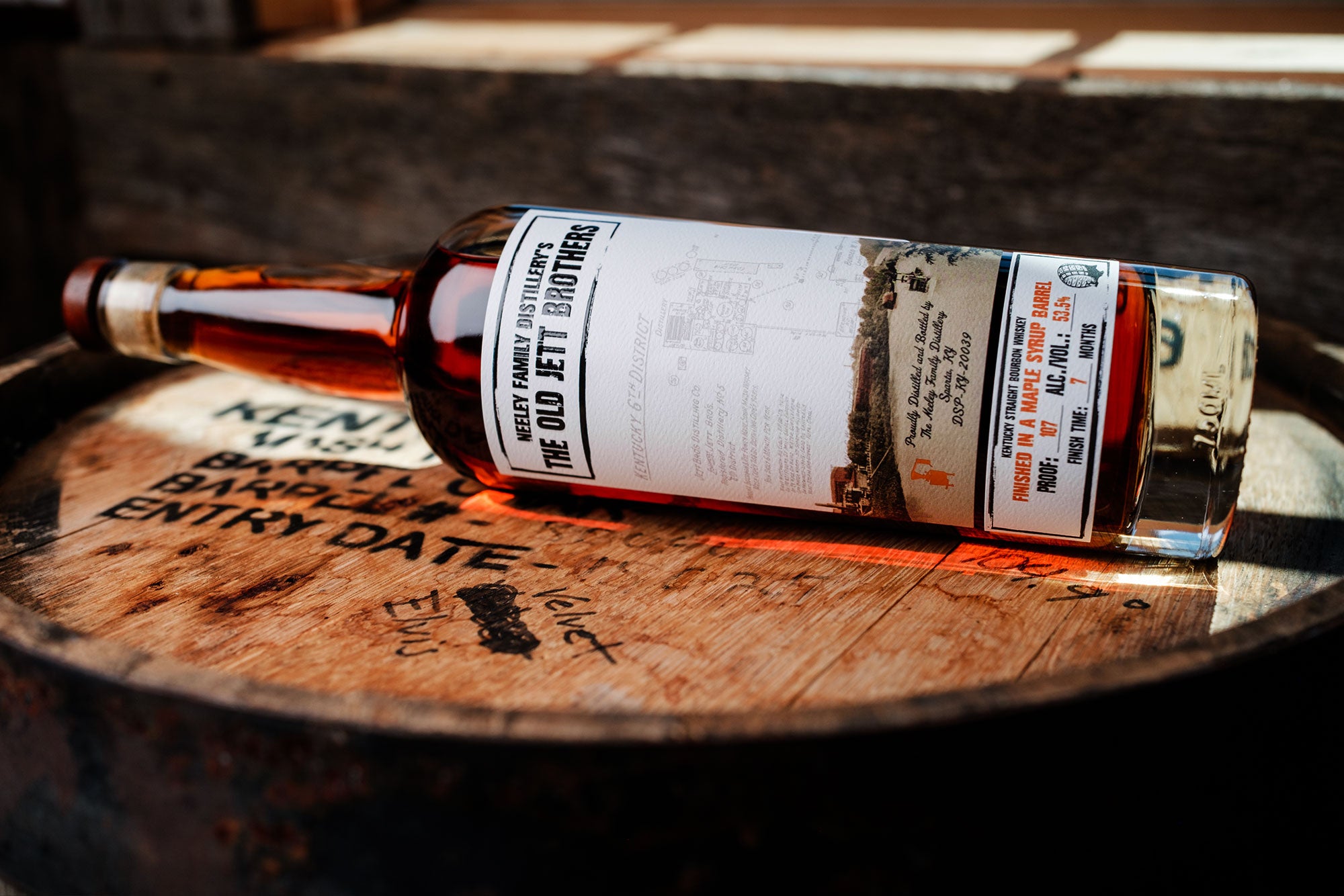 A bottle of Neeley Family Distillery The Old Jett Brothers Whiskey over a wooden barrel